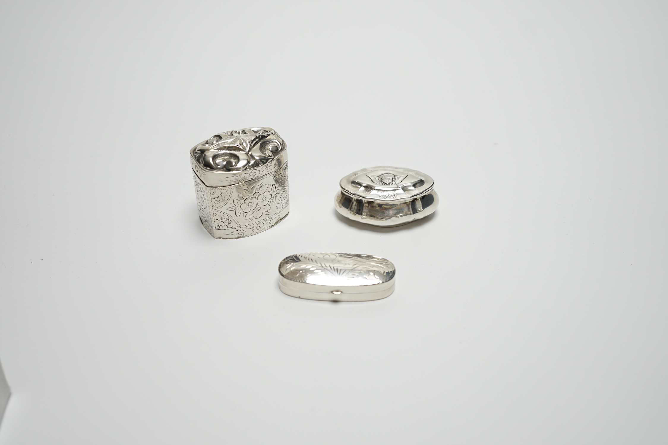 A late Victorian silver pill box with Reynold's Angel decorated cover, 47mm, a modern silver pill box and a Dutch white metal box.